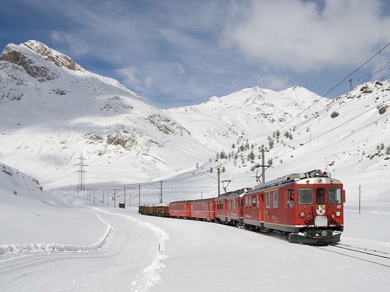 Red cogwheel mountain train climbing above a valley in the Swiss Alps